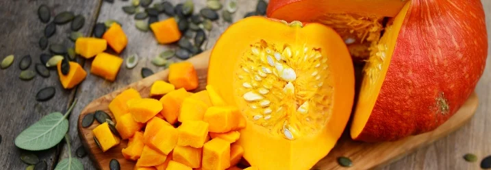 Geschnittener und ganzer Kürbis auf einem Holzbrett